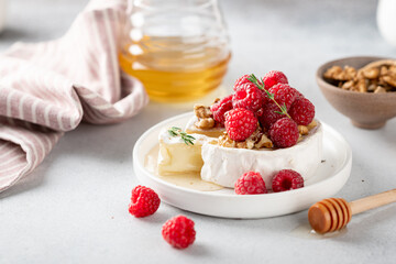 sliced brie cheese with raspberries, honey and walnuts . Selective focus, white background