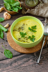 Spinach soup with cream on a rustic wooden table. Copy space.