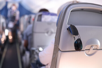 Sunglasses are placed on the passenger seat on plane. Summer vacation and travel concept