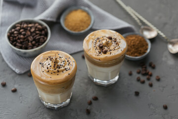 Glass of Iced Dalgona Coffee, trendy fluffy creamy whipped coffee and milk on grey background.