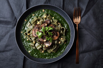 Spirulina pasta with mushrooms, spinach sauce and pine nuts