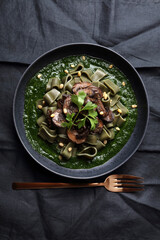 Spirulina pasta with mushrooms, spinach sauce and pine nuts
