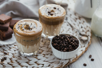 Glass of Iced Dalgona Coffee, trendy fluffy creamy whipped coffee and milk on white wooden background.