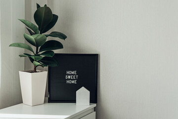 Inspirational quote home sweet home on black letterboard. In light interior, lifestyle.
