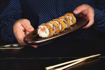 Hot fried sushi roll with salmon. Sushi menu. Japanese food. Hot fried sushi roll on black background
