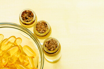 Golden fish oil capsules on a yellow background - the concept of health and natural marine vitamins.
