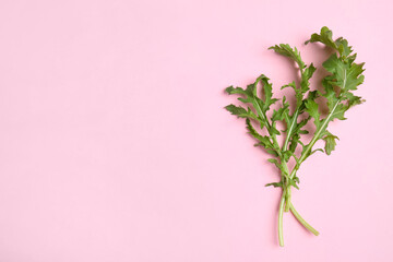 Fresh arugula on light pink background, flat lay. Space for text