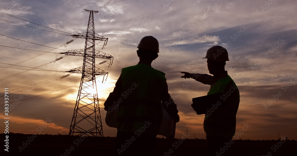 Wall mural two engineers in white safety helmets and green signal vests shake hands in front of a high-voltage 