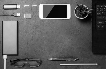 Electronic gadgets, succulent flower and stationery accessories on a black concrete background. Copy space