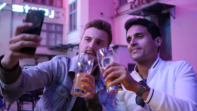 Making stories phone selfie two guys friends hang out drink beer on night city street bar