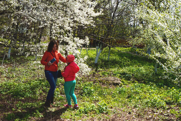 spring girls portrait over blooming tree, mom and daughter in a garden