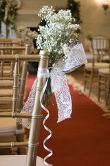 Ramo de flores blanca con lazo en sillas de ceremonia con alfombra roja