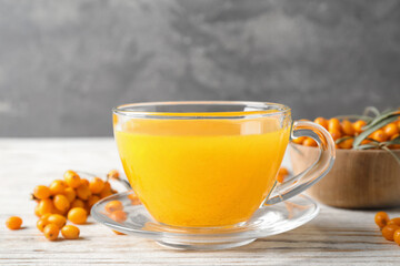 Fresh sea buckthorn tea on white wooden table, closeup
