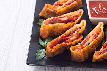 Pizza roll stromboli with cheese salami olives and tomatoes