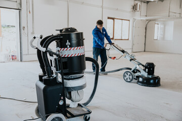 Construction worker using machine polishing surface floor smoothing and finishing hardener or epoxy...