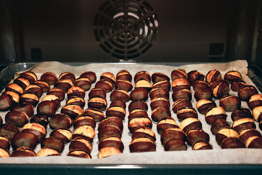 Oven Roasted Chestnuts Aligned One By One On A Parchment Paper.