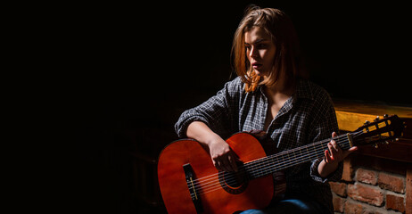 Obraz premium Woman playing guitar, holding an acoustic guitar in his hands. Music concept. Girl guitarist plays