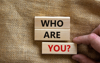 Male hand placing a block with word 'you' on blocks tower with words 'who are you'. Beautiful canvas background. Copy space. Business concept.