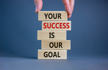 Wooden blocks with text 'your success is our goal'. Male hand. Beautiful grey background, copy...