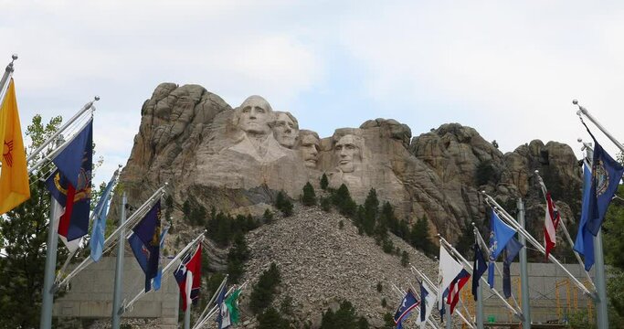 Mount Rushmore president monument mountain and flags 4K. National Memorial a colossal sculpture carved into granite in the Black Hills South Dakota. President Washington, Lincoln, Jefferson and Roosev