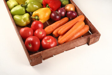 Juicy ripe vegetables on a wooden tray. Tomatoes, carrots, peppers and onions