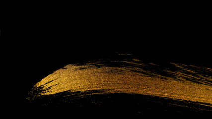 Trace of golden paint with a brush on a black background.