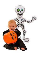 Beautiful and funny baby dressed as a vampire with a skeleton doll and a pumpkin for the Halloween party. Trick or Treating