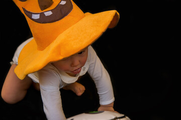 Beautiful Baby On A Black Background With A Pumpkin And A Pumpkin Hat On Halloween. Ask For Candy...