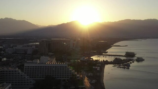 Sunrise over Eilat and The Red Sea, with waterfront hotels and Edom mountain ridge in the horizon, Aerial view.
