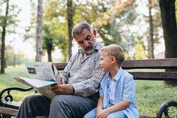 grandfather and grandson sitting on the bench in park