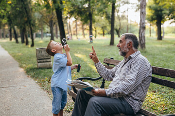 Obraz premium grandfather and grandson sitting on the bench in park