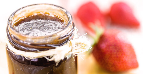 organic strawberry jam, handmade candy, with copper pot in the background with defocused fruits