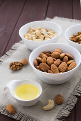 diet food concept, almonds, walnuts and cashew nuts with oil on a wooden table