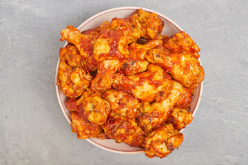Buffalo chicken wings in a plate on a gray concrete background, copy space