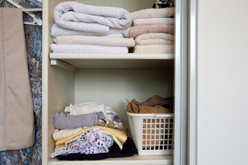 Fototapeta na wymiar Full closet with clothes and Stack of towels in white wooden closet, organization and storage