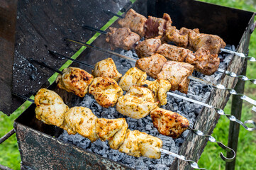 Raw meat cooking on skewers on barbecue grill. Close up.