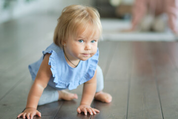 childhood, babyhood and people concept. happy little baby girl sitting on a wooden floor at home.