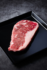 Fototapeta na wymiar raw marbled beef steak on a dish and stone background 