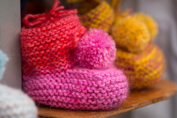 Handmade colorful knitted woolen baby's bootees, made from organic warm wool. Pink red and yellow infant newborn kid first socks with funny sump, made with love 