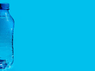 Wet plastic bottle of water on blue background with place for text, logo, design. 