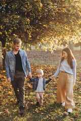 happy family mother father and baby on autumn walk in the park