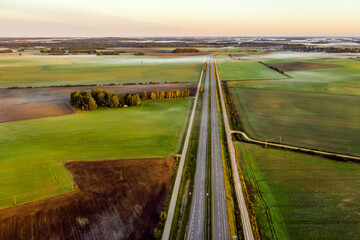 Aerial view of a highway passing through agricultural fields at sunrise