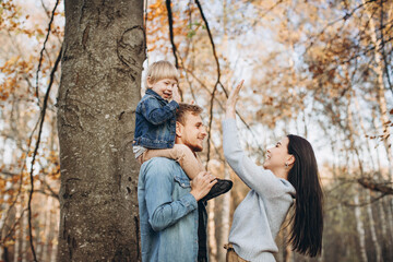 Family playing in autumn park having fun.