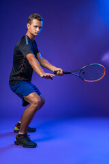 Young tennis player in action against purple background