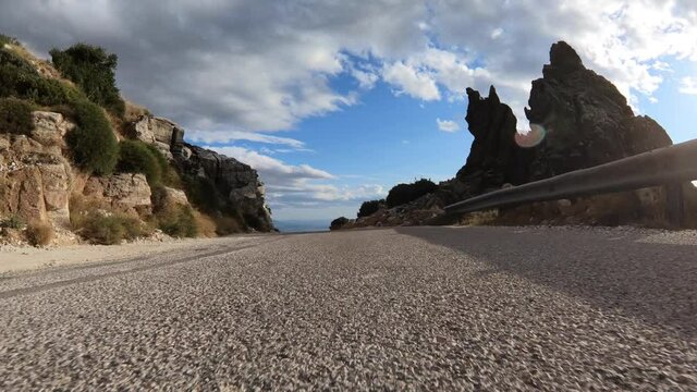 Fast tracking video from asphalt road perspective through a winding bumpy mountain road with with clear blue skies