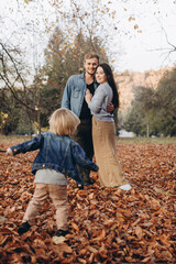 happy family mother father and baby on autumn walk in the park