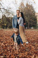 Fototapeta premium happy family mother father and baby on autumn walk in the park