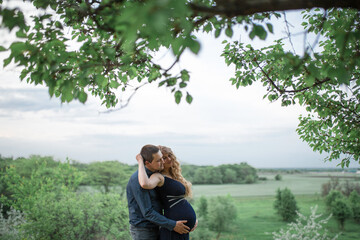 A loving couple walks in the field, the girl is pregnant. Walk in the fresh air. Love and care