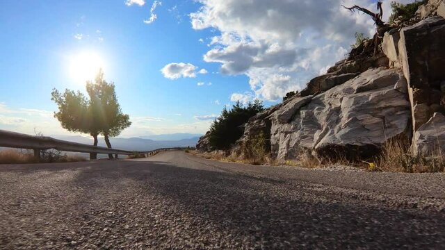 Fast tracking video from asphalt road perspective through a winding bumpy mountain road with with clear blue skies