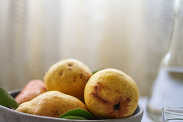 A bowl of fresh pears and a bottle of pear brandy.